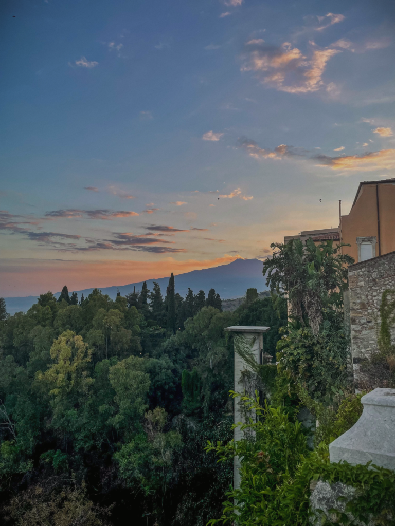 Stunning view of Taormina in Italy with its charming hillside town and the imposing Mount Etna volcano nearby.