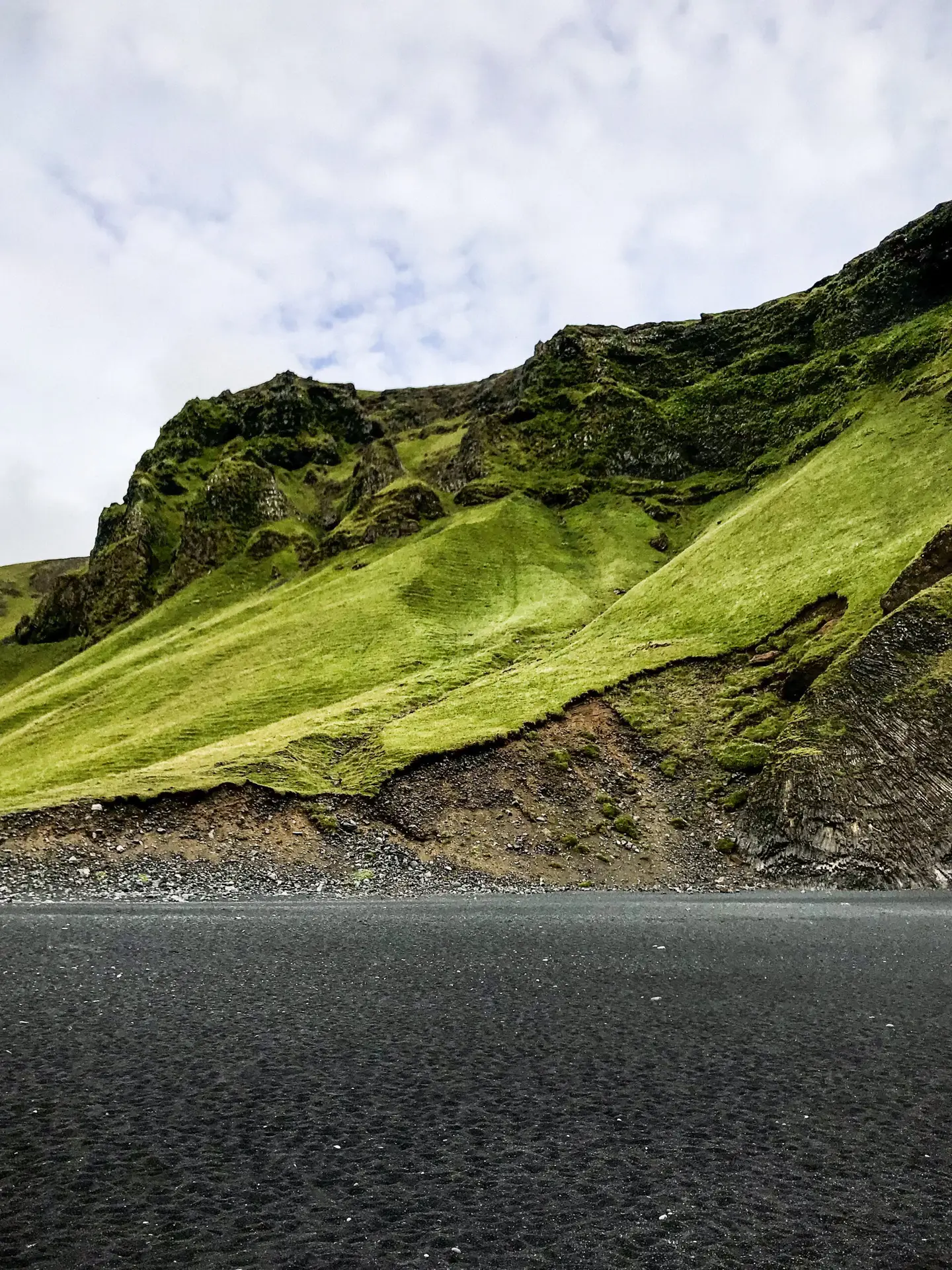 Black sand beach contrasting green hills in Iceland